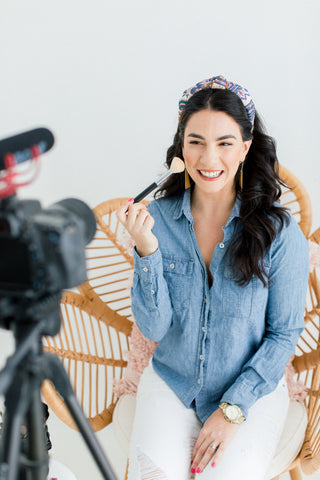 Beauty expert Claire Ashley is posing in front of a video camera applying makeup. 