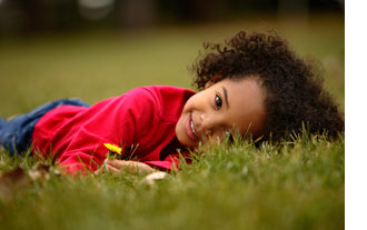 little girl in grass with dandelions