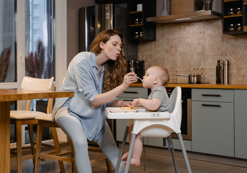 Mom feeding a baby around 6 months old solid food.