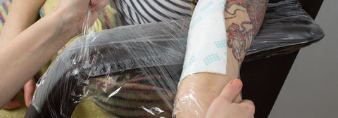 applying adhesive wrap to new tattoo
