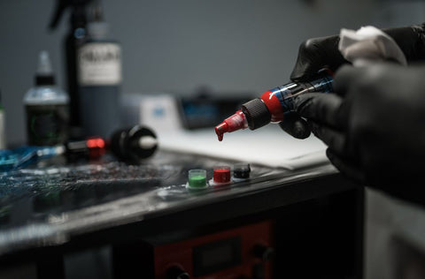 Tattoo artist with preparing ink for tattooing