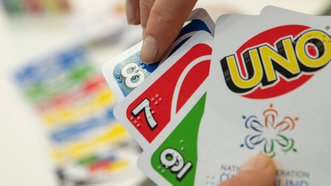 Someone holding and touching Braille Uno cards.