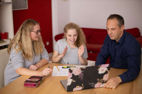 A man and woman help a girl do homework