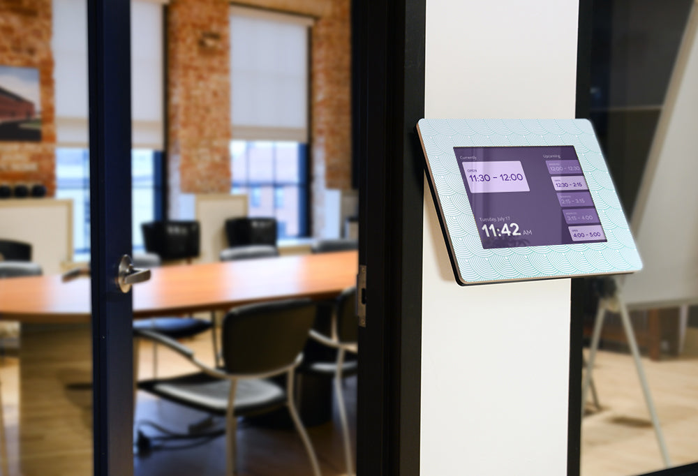An Angled Wall Mount kiosk mounted outside of a conference room, displaying a room schedule.