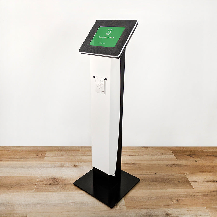 A standing kiosk with a printer slot for receipts. The iPad screen displays a 'Printing...' status message.