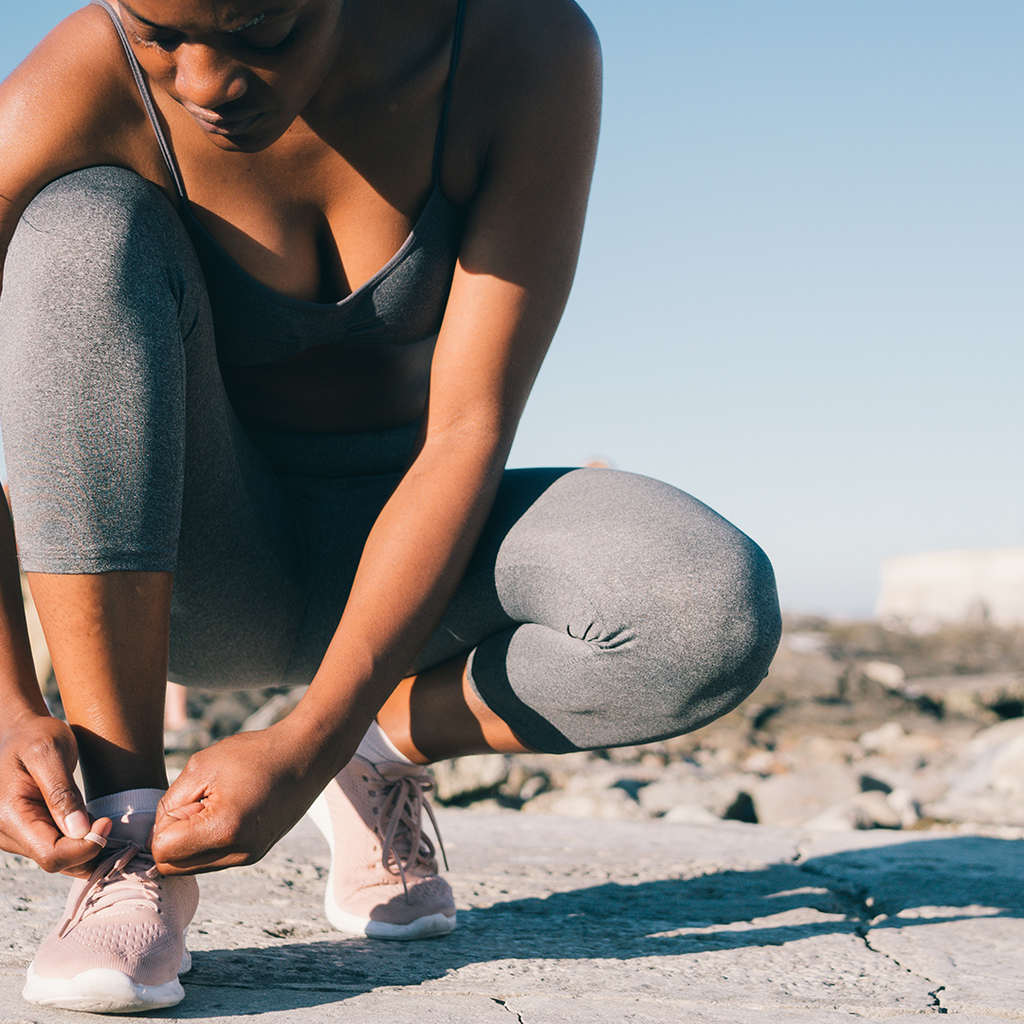 Girl tying shoe laces outside