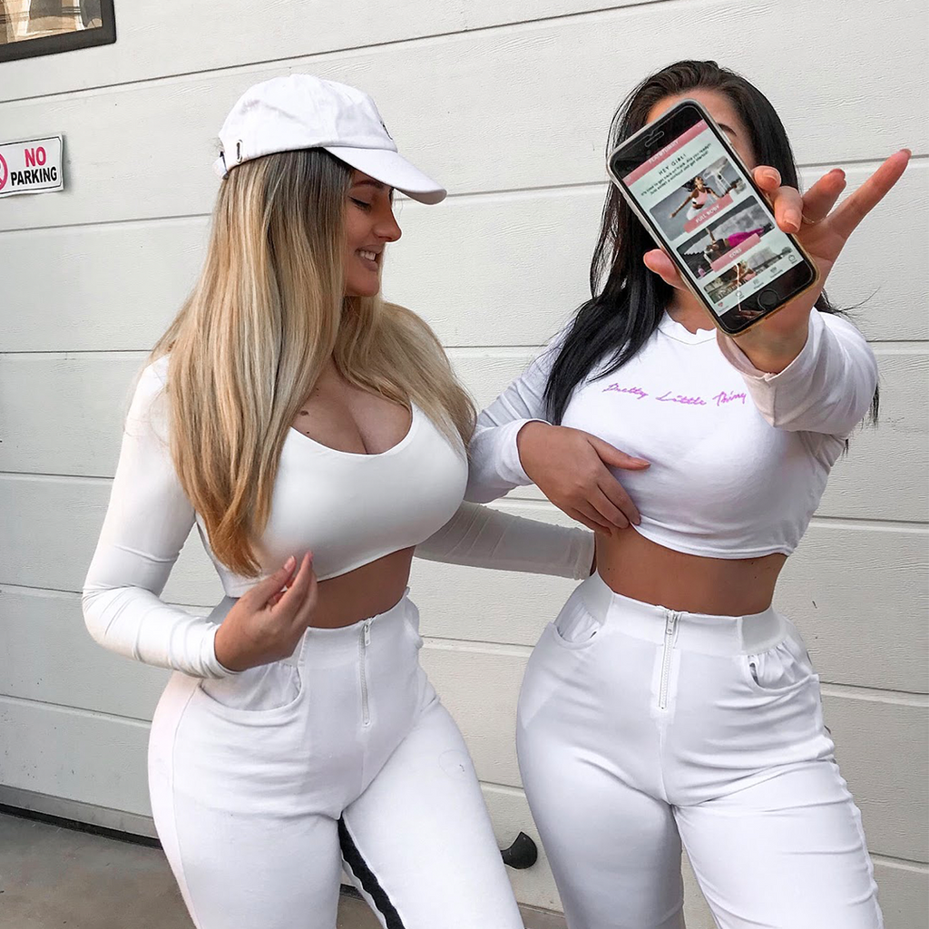 Two girls wearing white holding a phone