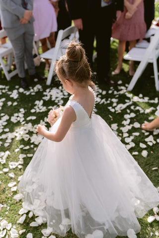 Little flower girl walking down the aisle in beautiful satin and tulle dress with V-neck decorated with beads