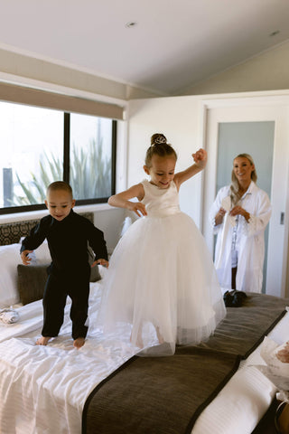 Little flower girl and page boy at wedding day of their mother having fun by jumping on a bed