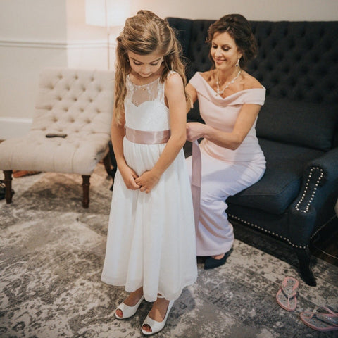 Flower girl in her gorgeous Roselle dress is standing and waiting till mom ties a sash. Roselle, Ana Balahan. Sydney, Australia.