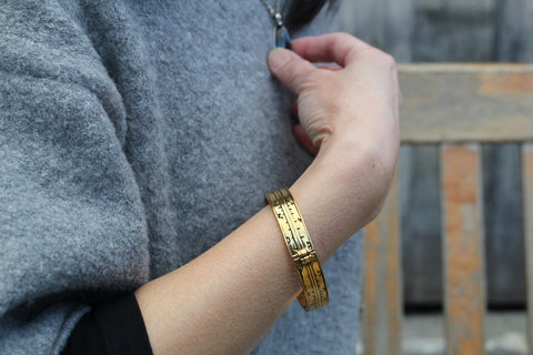 Model wearing our Brass Pocket Dial bangle, sat on a bench in the Shakespeare Birthplace garden