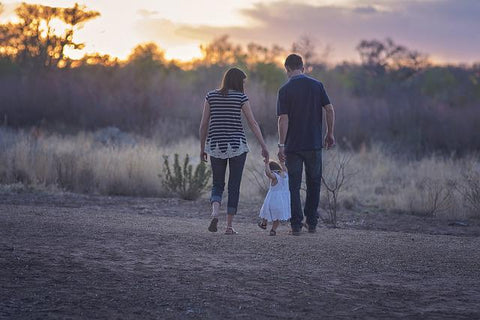 Mom and dad holding a child's hand, going for a walk together.