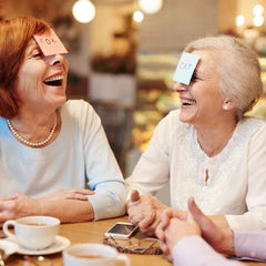 Two older women, having a game night, and laughing.