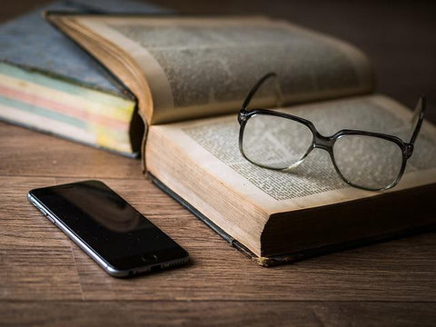 Phone next to scriptures with glasses on them.