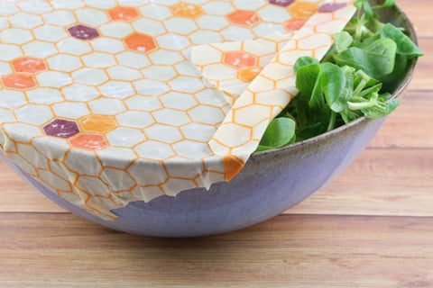 beeswax wrap being used on a container with salad