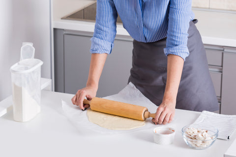 a woman using a white parchment paper to make pizza