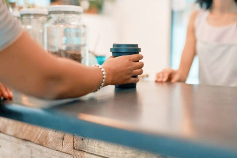 Netherlands: New rule for plastic to-go packaging from July - someone using s reusable coffee cup