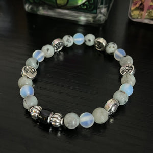 cosmic gemstone bracelet with a mood bead and a combination of sun/moon face charms, rainbow moonstone, and opalite
