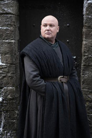 Varys from Game of Thrones standing in black clothes