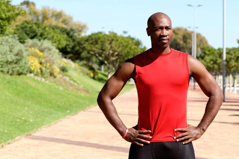 Shaved headed men standing in a red sleeveless shirt 