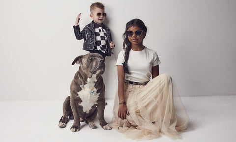 jeune fille qui pose avec un petit garçon et un chien, tous portent un bijou de Billionaire Baby