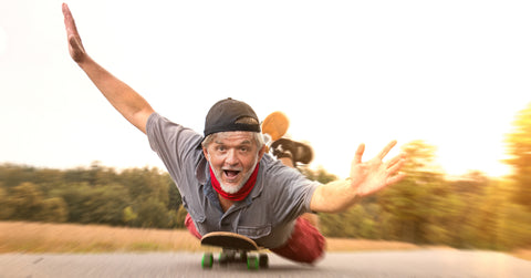 Mann fährt bäuchlings auf einem Skateboard - sinnbildlich für Lebensfreude