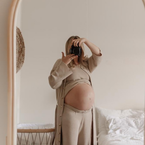 pregnant photographer taking a self portrait with her belly out & excited about meeting her baby.