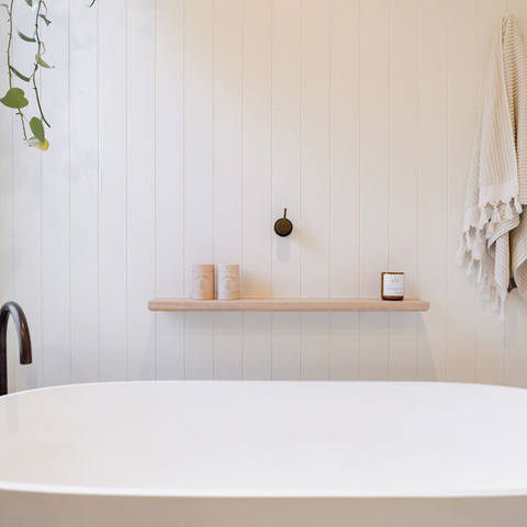 A modern bathtub in a calming environment. There are postpartum bath salts on the shelf. It could be a calming place to manage early labour pains or prepare for birth in the early stages of labour.