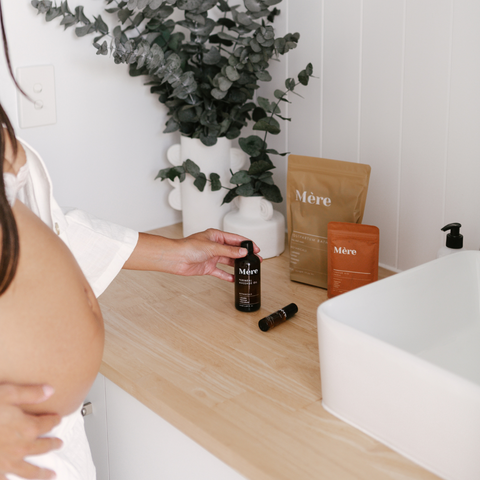 A pregnant woman is slightly out of frame as she looks at what natural postpartum care products to pack into her hospital bag. 