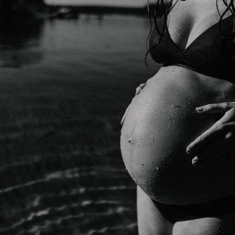 pregnant woman holding her pregnant belly in black and white photo