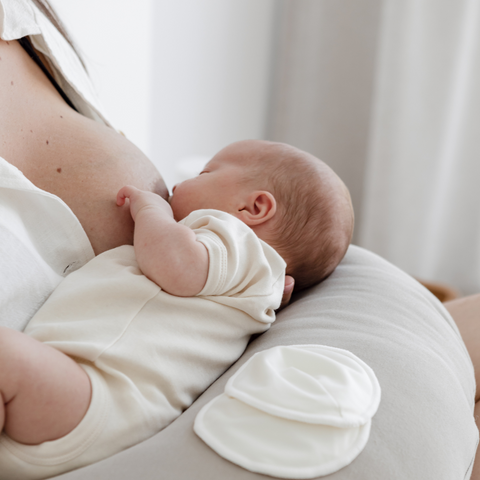 A breastfeeding support pillow props up a newborn learning to feed. 