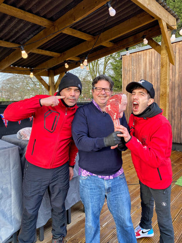 gruppo di tre persone tiene in mano un pezzo di carne