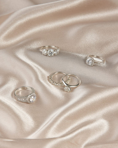 engagement ring guide | Five silver engagement rings on a silk background.