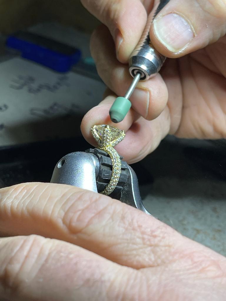 Pair of hands using machinery to polish ring