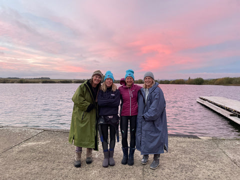 Group of women by the water with the sunset behind them