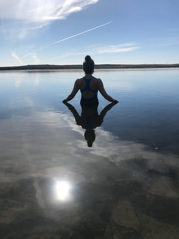Silhouette of someone from behind, standing still in the calm water