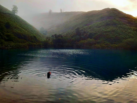 Lou Holmes swimming in a lake surrounded by hills