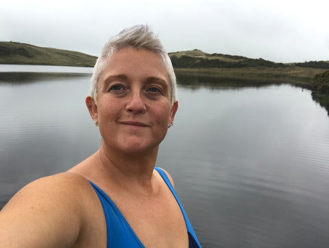 Sam facing the camera and smiling with the water behind her