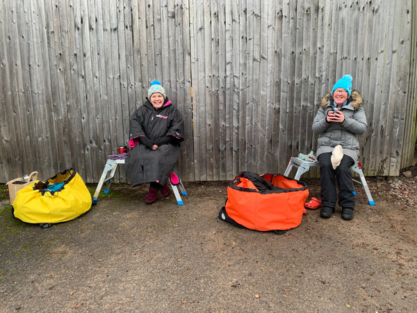 Judie and Kitty sitting next to their Turtleback outdoor swimming bags after a swim. 