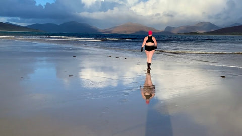 Woman in a swimming costume walking away from the camera into the sea. 