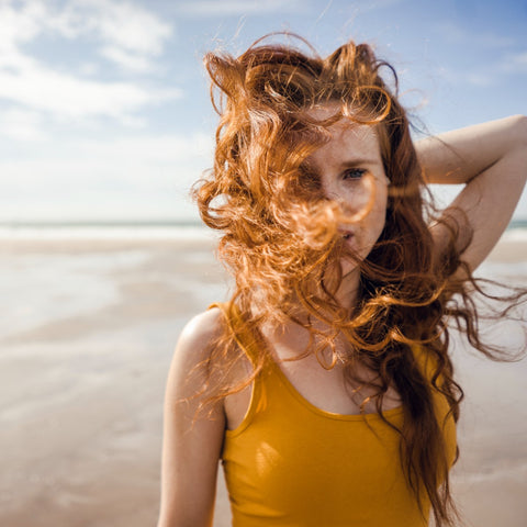 A young woman with red hair at the beach.