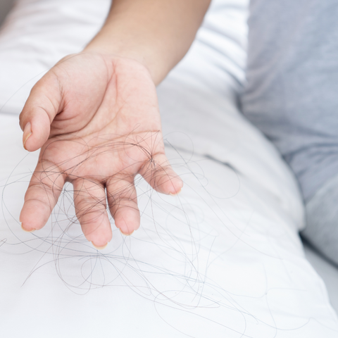 A woman showing her loose hairs on her pillow.