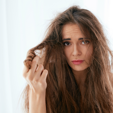 A woman examining her hair breakage and split ends.