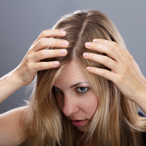 A young woman examining her hair for hair miniaturization.