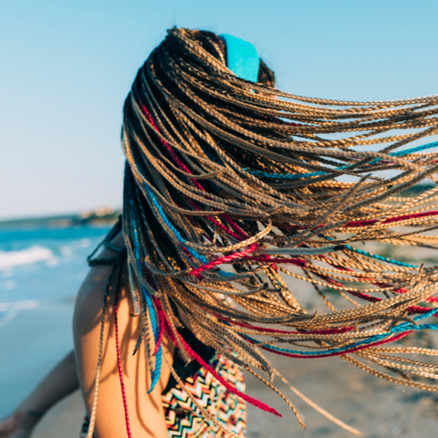 A woman at the beach with long, beautiful braids.