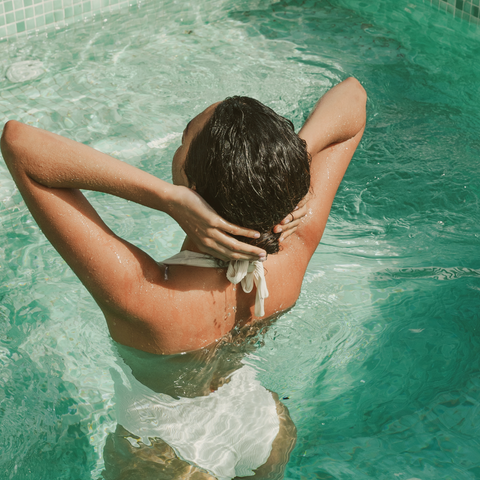 A woman at the pool with wet hair.