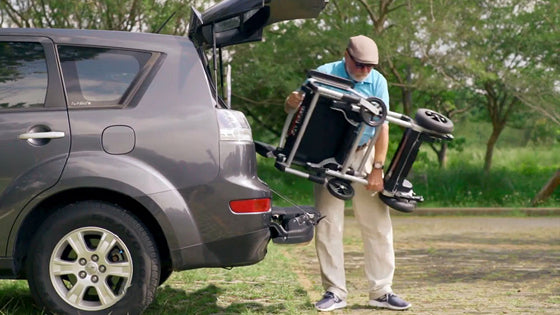 Man putting a lightweight wheelchair in car trunk