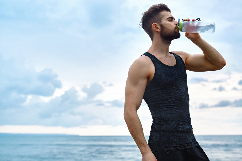 Man hydrates with aquamin after a workout on the beach