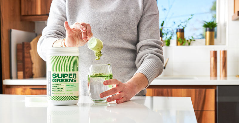 super greens super fruit supplement being poured into a glass of water