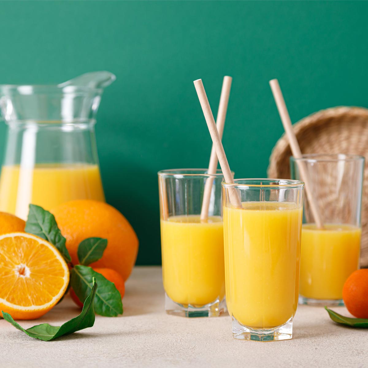 An electrolytes drink sits in glasses and a pitcher surrounded by fresh oranges